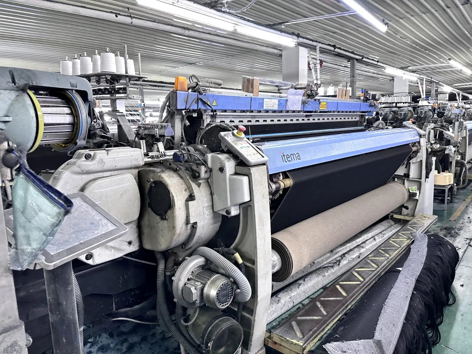 Air-jet weaving loom running dark fabric on a mill floor