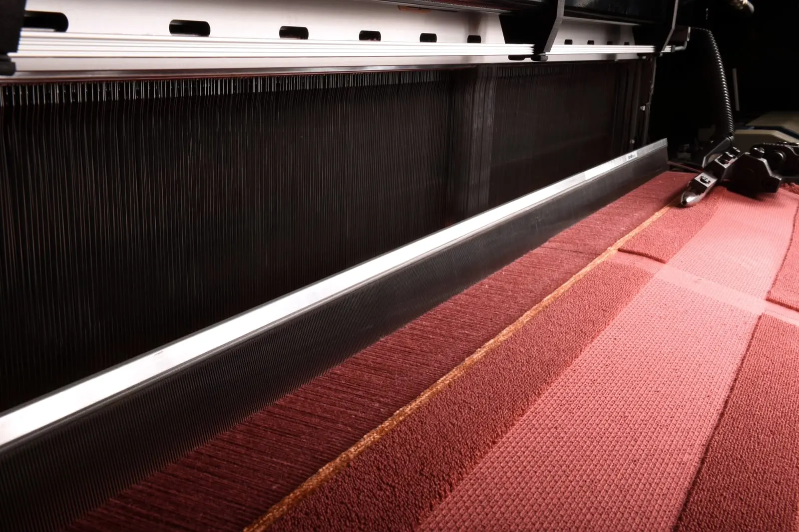 Red carpet being woven on a carpet loom