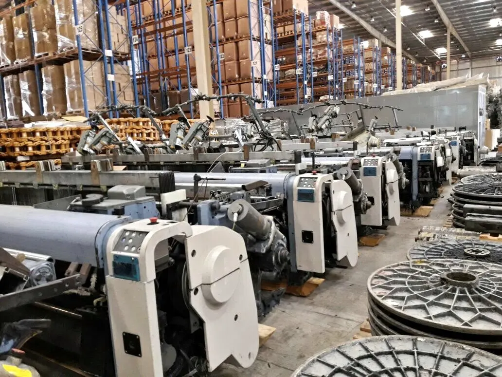 Used air-jet looms lined up in a warehouse before shipping