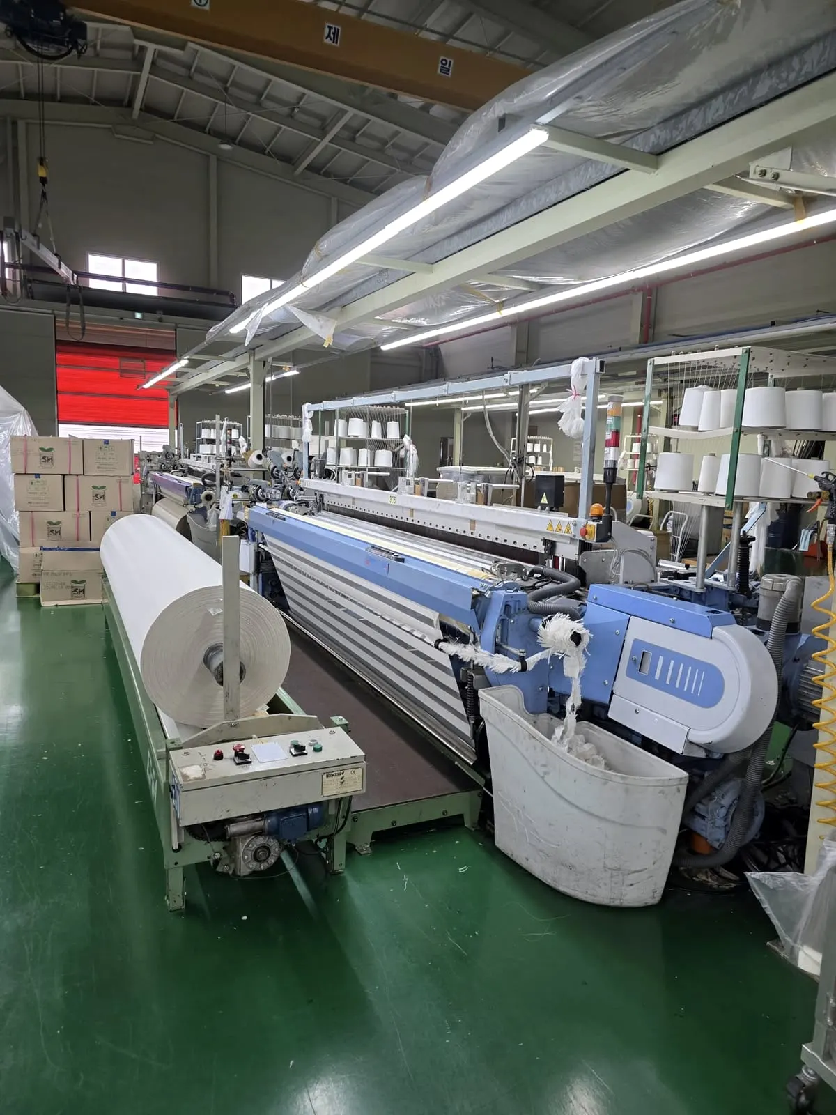 Weaving hall with air-jet looms and yarn on the creel